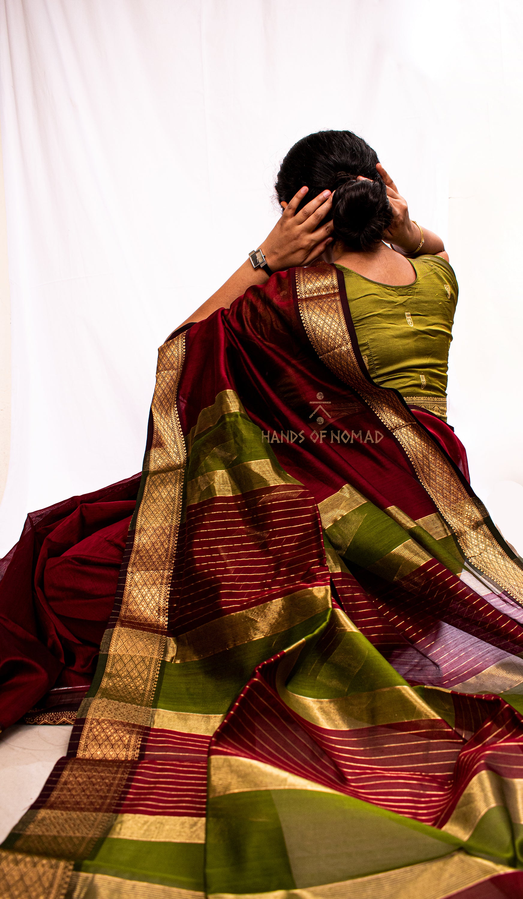 Woman in a traditional maroon and green Cotton Silk Maheshwari saree.
