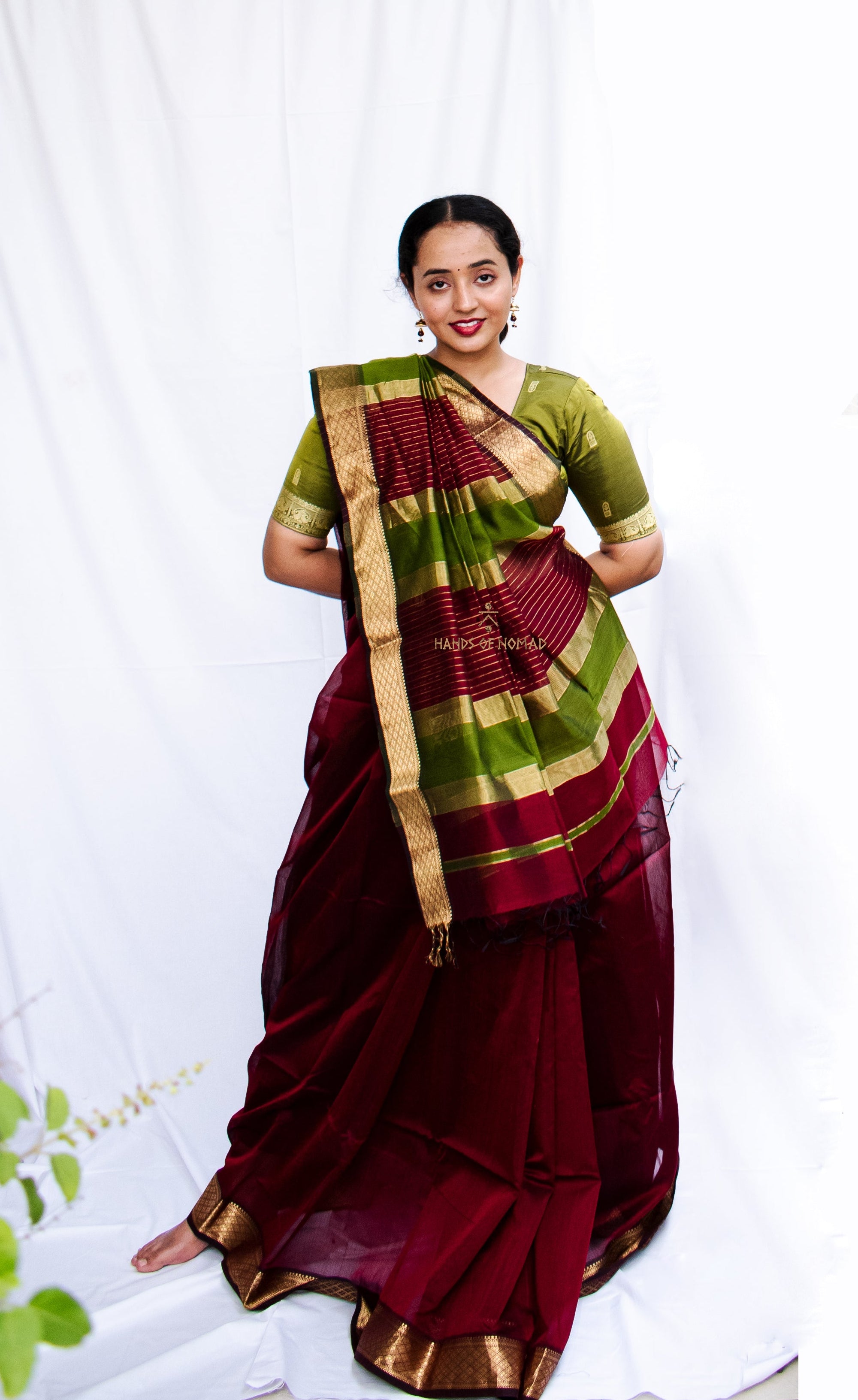 Woman in a traditional maroon and green Cotton Silk Maheshwari saree.