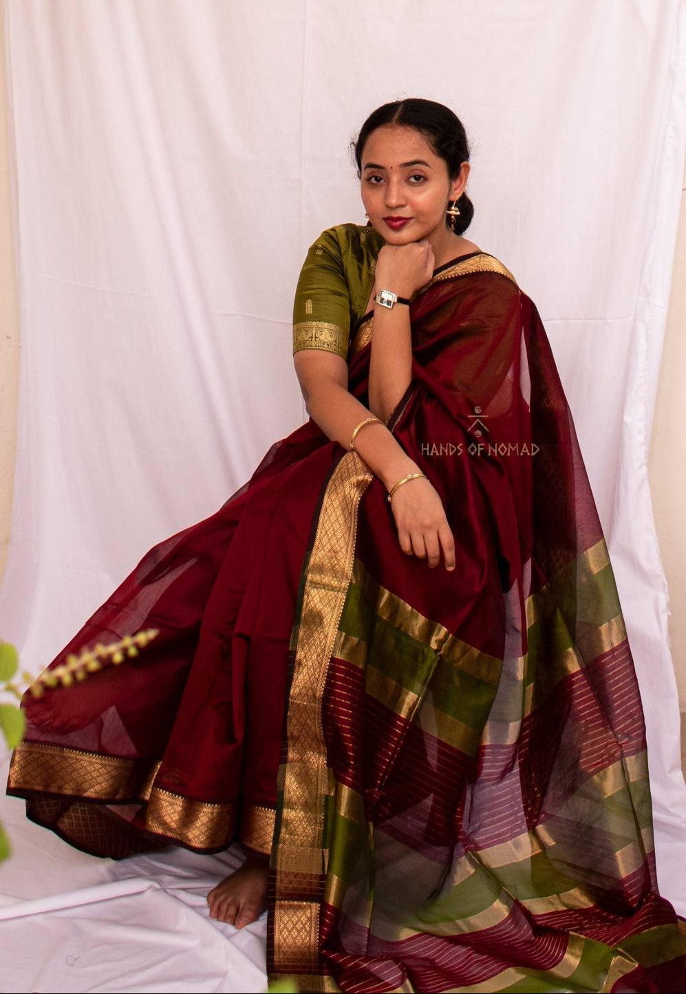 Woman in a traditional maroon and green Cotton Silk Maheshwari saree.