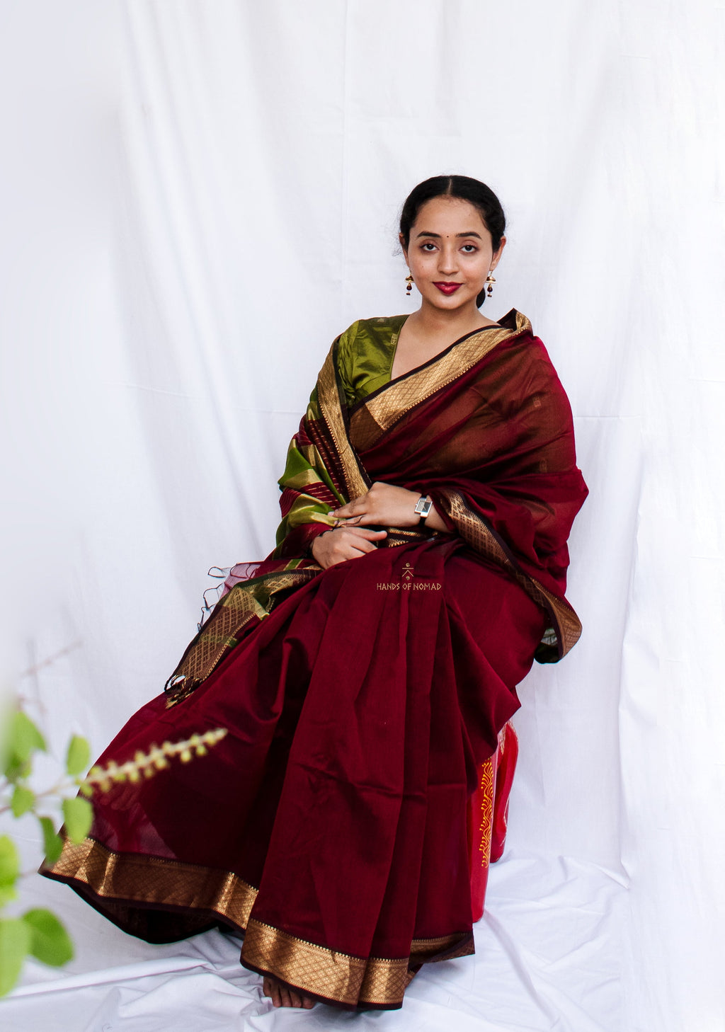 Woman in a traditional maroon and green Cotton Silk Maheshwari saree.